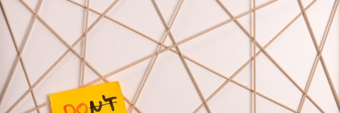 Bright yellow sticky note with motivational message on an abstract geometric design background.